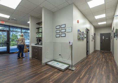 A woman stands in a hallway with a dog beside her